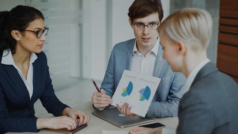 Three colleagues reviewing charts at a desk